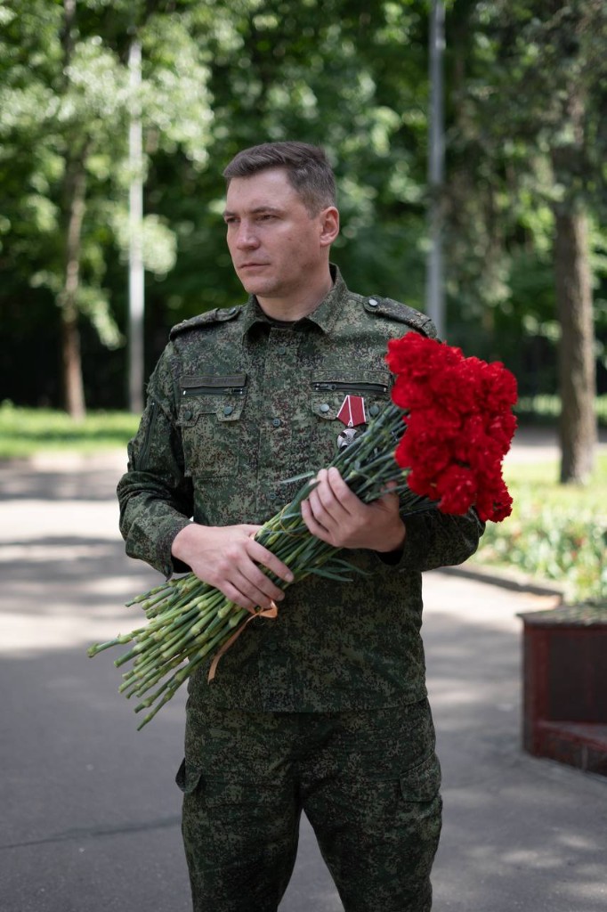 Шалаев Александр Владимирович с букетом гвоздик у мемориала